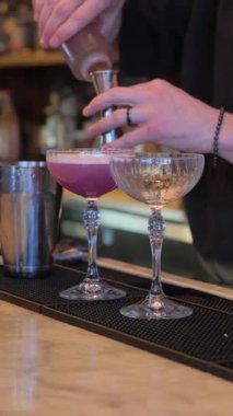 Çok yetenekli bir barmen zarif ve renkli kokteyller hazırlıyor. Güzel bir cam eşyayla.