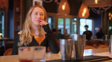 Genç bir kadın içkisinin tadını modern gece hayatının gerçek özünü yansıtan şık bir barda çıkarmayı sever.
