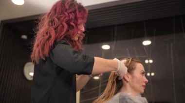 Yetenekli bir stilist, güzellik ve yaratıcılıkla dolu canlı bir salon atmosferinde parlak saç rengini uygular.