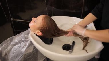 Sade bir kuaför salonunda etkili saç bakım teknikleri ve uygulamalarını vurgulayan bir saç yıkama seansı gerçekleşir.