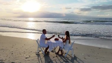 Aşık bir çift gün batımında sahilde keyifli bir akşam yemeği yer. Romantik bir atmosferle okyanus manzarasını birleştirir.