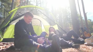 Neşeli bir aile, parlak bir çadırın yanındaki güzel ormanda kamp deneyimlerinin keyfini çıkarıyor.