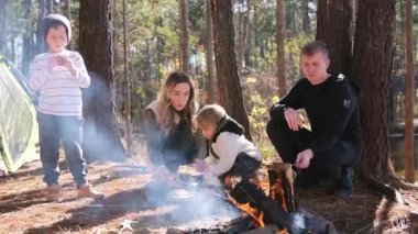 Sevgi dolu bir aile ormanda kamp ateşinin yanında eğleniyor. Aile kahkahalarla dolu..