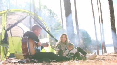 Kocasının gitarını çalan bir kadın sakin bir göl kenarında, gerçekten kaygısız bir açık hava tatili sizi bekliyor.