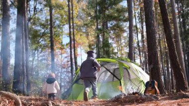 Parlak bir çadır ve gitarın etrafında eğlenen ve eğlenen çocuklarla dolu keyifli bir kamp sahnesi.