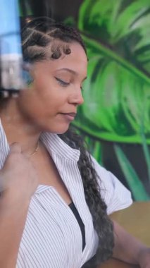 Afro-Amerikalı bir kadın, rahat ve modern bir kafe ortamında dinlenirken huzur içinde mola veriyor. Dikey video.