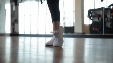 Moda beyaz spor ayakkabılarında gösterilen enerjik ayak hareketlerinin yakın görüntüsü, hem fitness hem de stili vurguluyor.