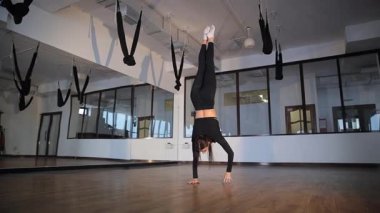 Yetenekli bir sanatçı şık siyah ipeklerle dolu canlı bir fitness stüdyosunda etkileyici bir amuda kalkar..