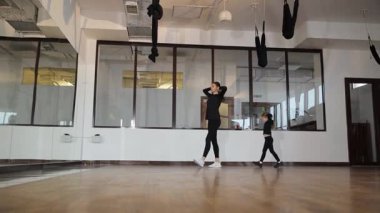 Neşeli bir sahnede, bir anne çocuğuyla canlı bir stüdyoda dans ediyor, mutluluk ve hareket sergiliyor..