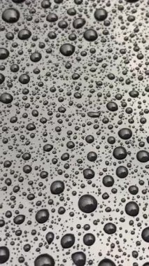 Metalik bir yüzeyde biriken su damlacıklarının güzel yakın plan görüntüsü, doku ve yansımaları gösteriyor..