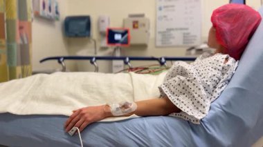 Bir hasta hastane odasında dinlenir, tıbbi ekipmanlara bağlanır..