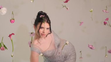 Zarif bir model soluk soluğa kalmış çiçeklerin arasında zarif bir poz vererek güzelliğini ve zarafetini ön plana çıkarıyor.