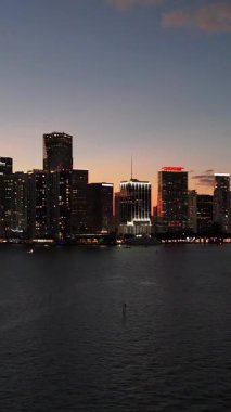 Günbatımında Miami ufuk çizgisi, gece ışıkları, Florida üzerinde hava aracı manzarası. Dikey video. 