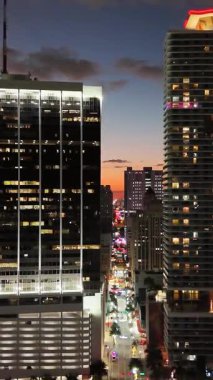 Gündoğumunda soluk gece ışıkları ve Florida üzerinde hava aracı manzaralı Miami silueti. Dikey video. 