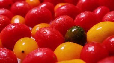 Taze kiraz domatesleri, güzelce serpilmiş ve üzerine su damlaları serpiştirilmiş..