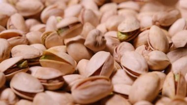 Çiğ fıstıkların yakın plan görüntüsü, eşsiz kabuklarını ve içindeki parlak yeşil çekirdekleri gösteriyor..