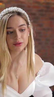 Gelinlikler, zarif iç dekorasyonlu bir gelinlik sergisinde sergileniyor. Dikey video.