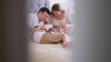 Neşeli aile, yeni doğmuş bebekle sıcak yatak odası ortamında hassas anları paylaşıyor..