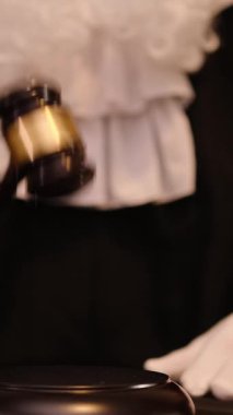 Yargıç tokmak kaldırılmış olarak mahkeme salonunda duruyor. Adalet ve yasal işlemleri sembolize ediyor. Dikey video. 