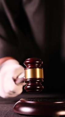 Kanun ve otoriteyi temsil eden tokmak, hukuk kitapları ve adalet sembolleriyle mahkeme salonu sahnesi. Dikey video.