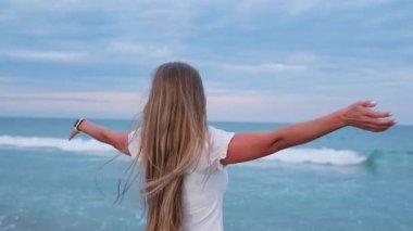 Tatil sırasında okyanus kıyısında havanın tadını çıkaran genç bir kadın. Özgürlüğü hissetmek.