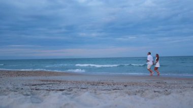 Mutlu bir çift okyanusun yakınındaki kumda koşuyor ve birbirlerine hayran..