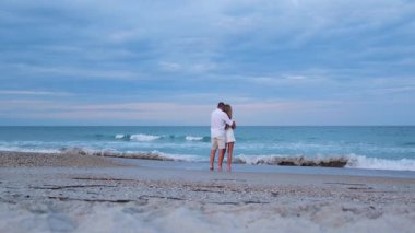 Birbirine aşık bir çift, okyanusta dinlenirken, su kenarında sarılır..