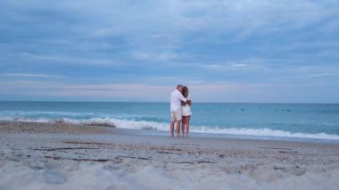 Kadın ve erkek sahilde yüz yüze duruyor, romantik bir anın tadını çıkarıyorlar.. 