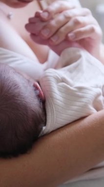 Sevgili anne bebeğini rahat ve şefkatle dolu sıcak, rahat bir odada emziriyor. Dikey video. 