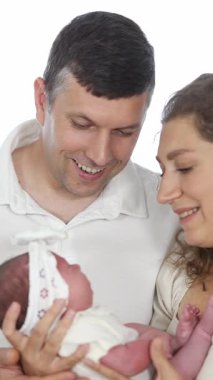 Sadık ebeveynler yeni doğan bebeklerini sevgiyle kucağına alarak aile mutluluğunu ve bağlantısını kutluyorlar. Dikey video. 