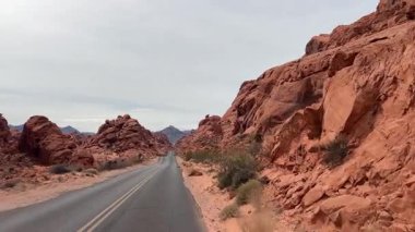Arizona, ABD 'de manzaralı bir yol boyunca nefes kesici manzaralar, yüksek kızıl kaya oluşumları ve dramatik çöl manzaralarıyla güzel çerçevelenmiş..