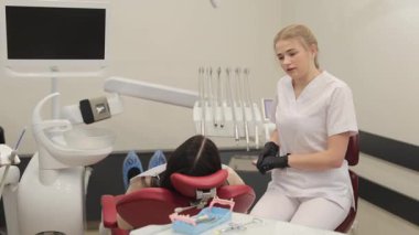 Bir diş hekimi, son derece gelişmiş ve modern bir diş sağlığı kliniği ortamında bir hastaya yardım etmektedir..