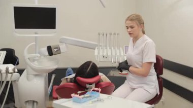 Çok yetenekli bir diş hekimi, modern ve eyalet dişçi bürosunda çalışan bir hastaya yardım eder..