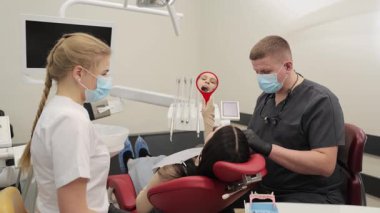 Profesyonel dişçi, temiz ve modern bir diş kliniğinde hastayı ustalıkla tedavi eder.. 