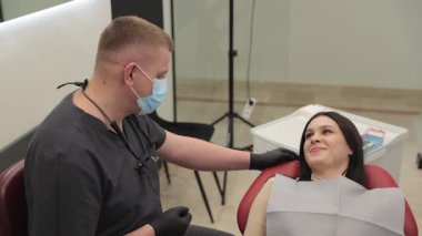 Gülümseyen bir hasta dişçi koltuğunda rahatça oturur ve muayene sırasında dişçiyle ilişki kurar..