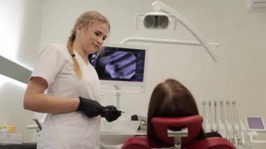 Bir dişçi asistanı, modern bir klinik ortamında bir hastayla ilgilenir, bakım ve profesyonelliği gösterir..