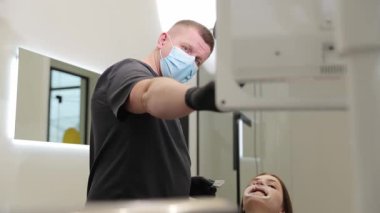 Modern bir diş kliniğinde, yetenekli bir dişçi bir prosedür uygularken, bir hasta mutlu bir şekilde ileri derecede bakım sergiler..