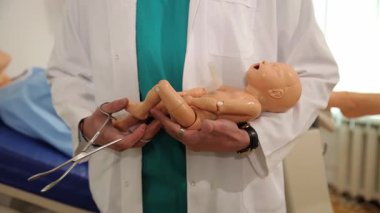 Yetenekli bir tıp uzmanı eğitim sırasında bebek mankeni kullanarak doğum teknikleri gösteriyor..