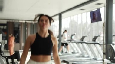 Bir kadın şık ve çağdaş bir spor salonunda enerjik bir egzersiz seansına katılır..