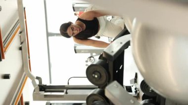 Spor salonunda ağırlık çalışan odaklı bir kadın modern bir spor salonunda çalışıyor. Dikey video