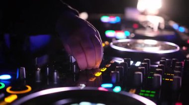 Bir DJ canlı performans sergiliyor, canlı ışıklar heyecan verici sahneyi aydınlatırken şarkıları ustaca karıştırıyor..