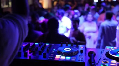 DJ gecesinin hareketli ve dinamik atmosferi dans eden kalabalık ve renkli, yanıp sönen ışıklarla dolu.