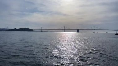 Suyun üzerinde uzanan, güneş ışığıyla aydınlatılan, sakin bir atmosfer yaratan güzel bir köprü manzarası..