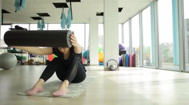 Kadın spor salonunda jimnastik aletlerini tutarken vücudunu eğiyor. Pilates. Vücut esnekliği. Sağlıklı vücut