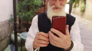 Yaşlı bir adam akıllı telefonunu kullanarak teknoloji ve Longheld gelenekleri arasındaki güçlü bağlantıyı gösteriyor.