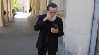 Olgun bir adam şehir ortamında akıllı telefonlarla derinden ilgilenir..