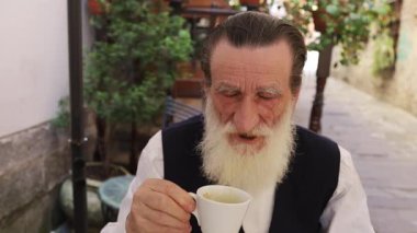 Kıdemli adam sessiz sedasız, yemyeşil bir ortamda çayını yudumluyor.. 