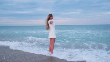 Güzel alacakaranlıkta okyanus dalgalarından hoşlanan sarışın kadın. Özgürlüğü hissetmek.