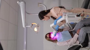 Yetenekli dişçi, ileri teknoloji ürünü aletler kullanan hastalara tam diş tedavisi uyguluyor.. 