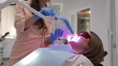 Modern diş muayenehanesinde parlak LED ışığıyla profesyonel diş beyazlatma tedavisi. 
